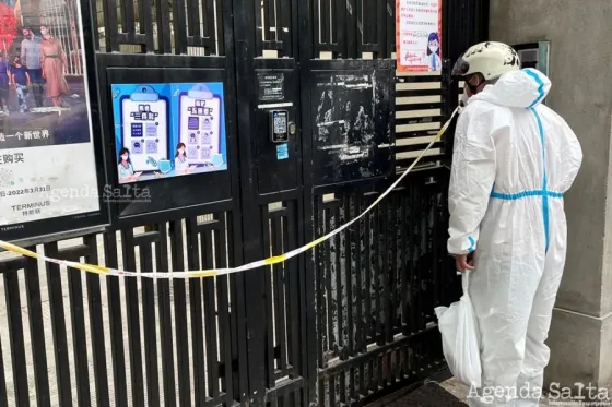 Un empleado de un delivery lleva comida a un edificio de departaments blindado por el nuevo brote de coronavirus en Shanghái, China, este sábado. Foto: REUTERS